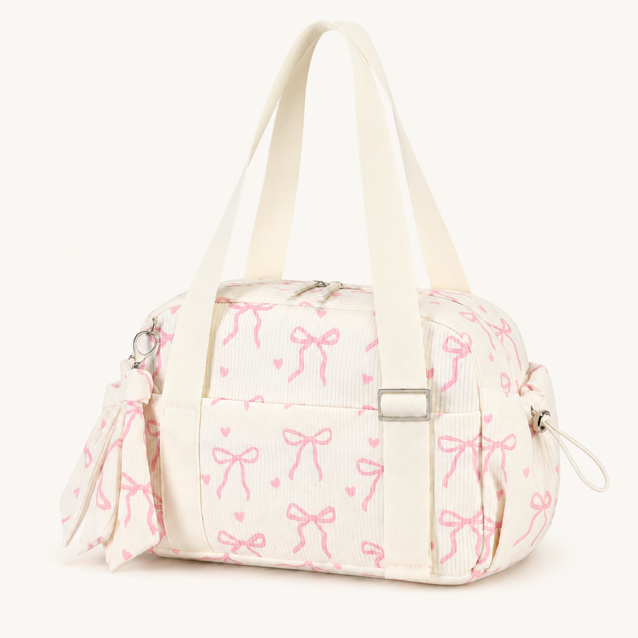 Cream mini gym bag with pink bow print, long carry handles, front pocket and side pockets on a warm off-white background.