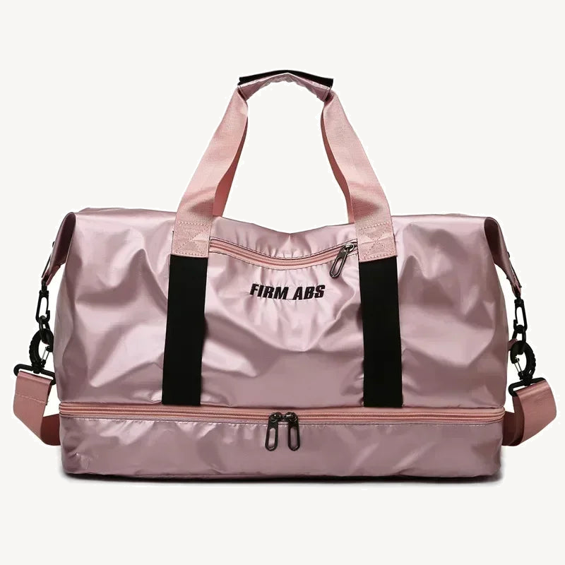 Pearlescent pink fitness duffel with black webbing, detachable shoulder strap, front zip pocket and lower zip compartment on a warm off-white background.